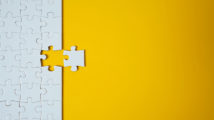 White jigsaw puzzle on yellow background. Team business success partnership or teamwork.