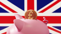 Piggy bank and pound coin over British flag background. Horizontal composition with copy space. Great use for savings concepts.